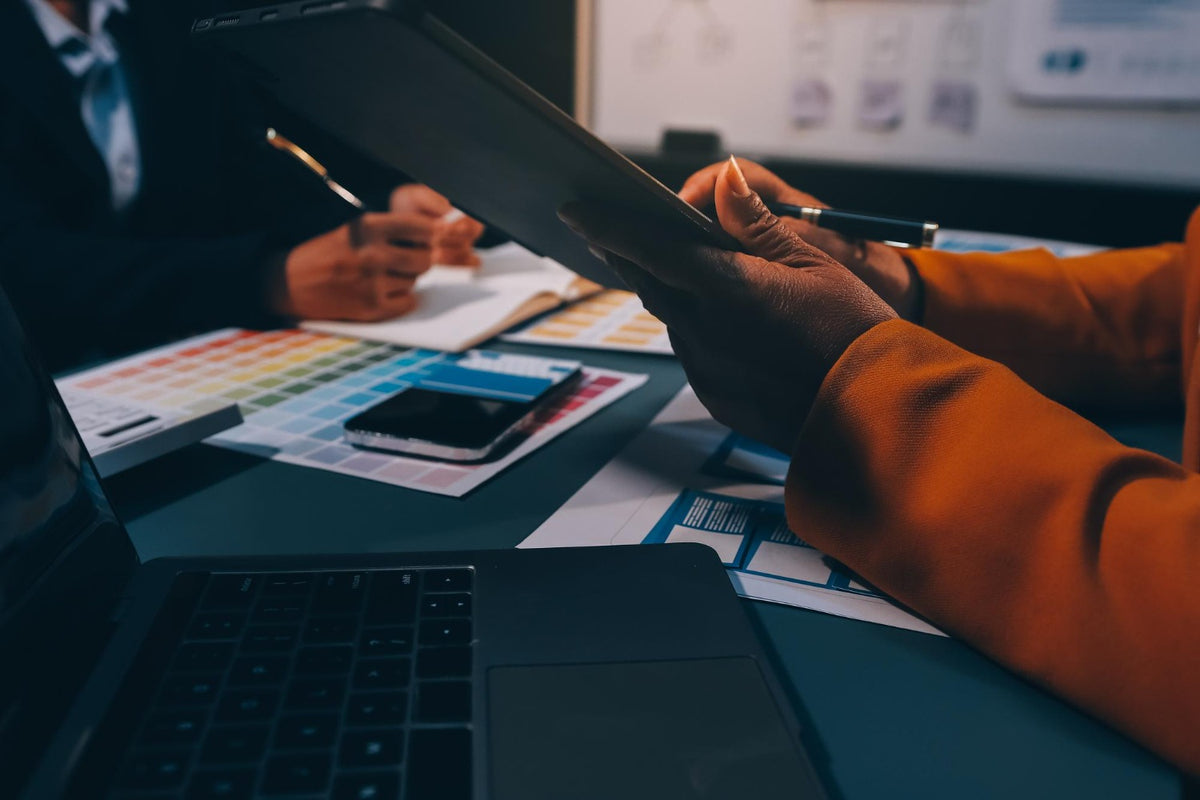 Person holding a tablet with design software on a desk with color swatches and a laptop. image: Menko  services pvt tld