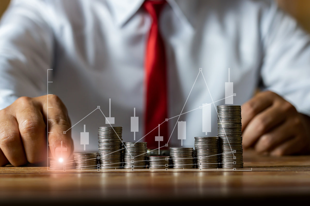 Person stacking coins on a table with financial graph overlay